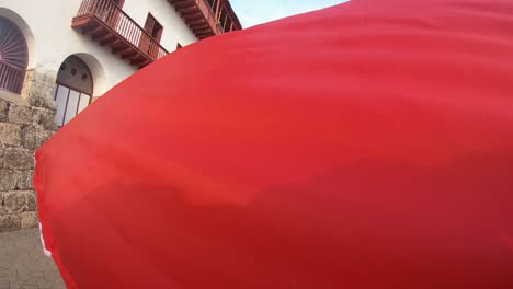 Ein-Großer-Und-Farbenfroher-Regenschirm-Ist-Zu-Sehen,-Während-Touristen-Die-Straße-Der-Altstadt-Von-Cartagena-De-Indias,-Kolumbien,-Entlanggehen