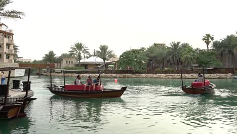 Tourists-Riding-The-Traditional-Abra-Boat-Sailing-At-The-Famous-Madinat-Jumeirah-In-Dubai,-United-Arab-Emirates
