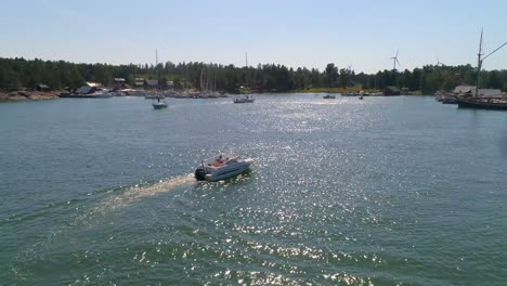 Aerial,-tracking,-drone-shot,-of-a-motorboat-arriving-at-a-harbor,-on-Hogsara-Island,-in-the-finnish-archipelago,-on-a-sunny,-summer-day,-in-Varsinais-suomi,-Finland
