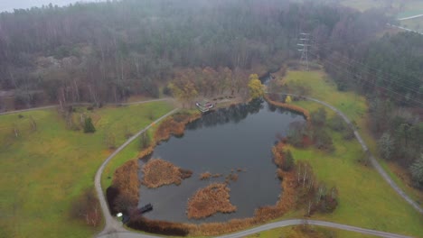 Aerial-footage-approaching-a-pond-located-in-a-nature-park-beside-Stockholm-University