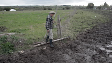 Farmer-closes-wire-fence-gate-in-a-farm,-full-shot