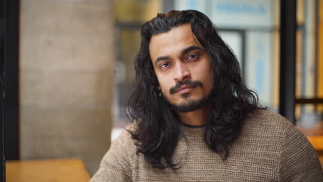 A-Closeup-Portrait-of-a-Contemplative-Indian-Man-in-Café-looking-into-the-Camera-on-a-Cold-Snowy-Day