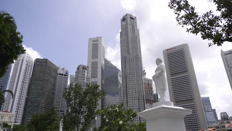 Skyscraper-office-buildings-in-the-Central-Business-District-of-Singapore,-Raffles-Place,-white-statue-monument-beside-Singapore-river