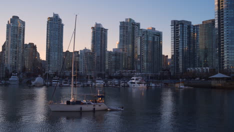 Ein-Von-Rechts-Nach-Links-Gedrehter-Dolly-Schoss-An-Einem-Großen-Segelboot-Vorbei,-Mit-Dem-Sonnenuntergang-In-Der-Innenstadt-Von-Vancouver-In-Der-Ferne