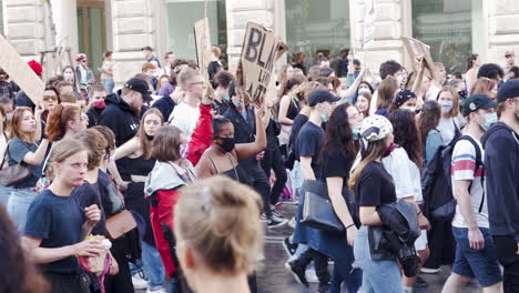Eine-Aufnahme-Einer-Gehenden-Menschenmenge,-Die-Schilder-Hochhält-Und-Gegen-Rassismus-In-Wien-Protestiert