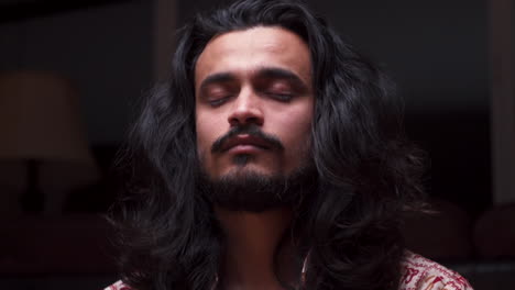 A-RIGHT-TO-LEFT-CLOSEUP-DOLLY-SHOT-of-a-Handsome-Indian-Man-Closing-His-Eyes-in-Preparation-for-Meditation