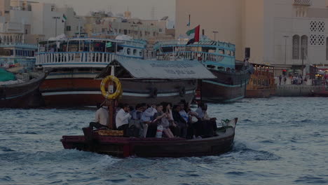 Abra-Ferry-Boats-With-Tourists-Crossing-At-The-Dubai-Creek-Near-The-Deira-Gold-Souk-In-Dubai,-UAE