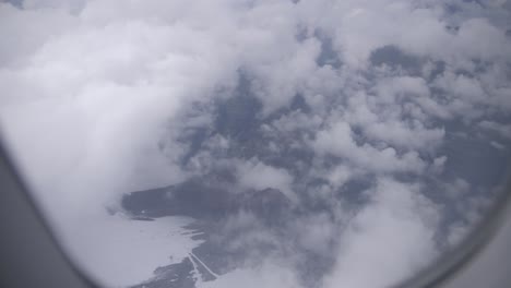 Foggy-view-out-of-plane-at-some-monuntains,-cloudy-day