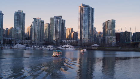 Eine-Totalaufnahme-Eines-Aquabusses,-Der-Zum-Hafen-Von-Yaletown-Fährt,-Mit-Dem-Sonnenuntergang-In-Der-Innenstadt-Von-Vancouver-In-Der-Ferne