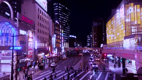 Future-looking-people-crossing-an-urban-city-street-at-night-with-neon-signs