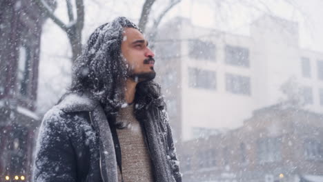 An-ORBITING-CLOSEUP-of-a-Young-Indian-Man-Looking-in-Awe-at-Historic-Downtown-Architecture-as-Snow-Falls-on-a-Cold-Winter-Day