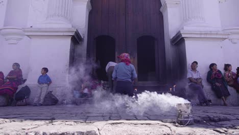 Entrance-of-an-old-catholic-church-in-Chichicastenango,-Guatemala,-while-a-man-performs-a-religius-ceremony
