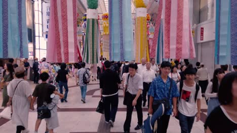 Gente-En-Una-Calle-Concurrida-Caminando-Entre-Serpentinas-De-Papel-Decorativas-Durante-El-Festival-De-Tanabata-En-Cámara-Lenta