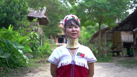 Beautiful-Kayan-Woman,-Giraffe-Woman-With-Flower-Headdress-Posing-At-The-Camera-From-The-Kayan-Hill-Tribe-In-Baan-Tong-Luang,-Chiang-Mai,-Thailand
