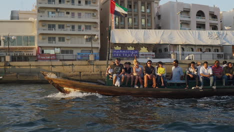 Tourists-At-The-Traditional-Abra-Boat-Cruising-In-Dubai-Creek-Near-Deira-Gold-Souk-In-Dubai,-UAE
