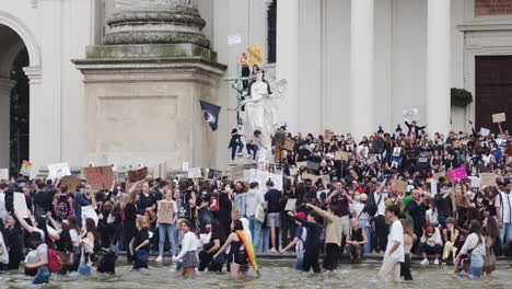 A-shot-of-a-crowd-protesting-against-racism-while-standing-in-a-fountain-in-front-of-a-building-in-Vienna