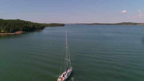 Aerial,-rising,-drone-shot,-of-a-sailboat-on-the-Gulf-of-Finland,-at-Hogsara-Island,-in-the-finnish-archipelago,-on-a-sunny,-summer-day,-in-Varsinais-Suomi