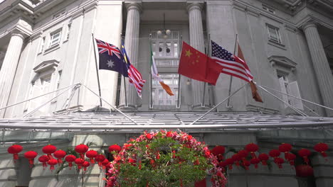 Flags-blowing-in-the-afternoon-breeze-at-the-main-entrance-lobby-of-The-Fullerton-Hotel-Singapore,-still-shot
