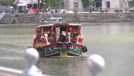 A-boat-ferrying-tourists-cruising-on-Singapore-river-towards-the-camera-footage-on-a-sunny-afternoon