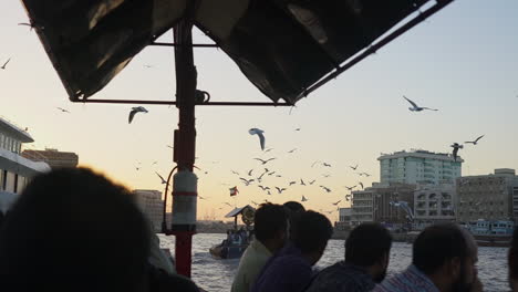 Riding-The-Famous-And-Traditional-Wooden-Abra-Boat-With-Seagulls-Flying-In-Dubai-Creek,-Dubai,-UAE