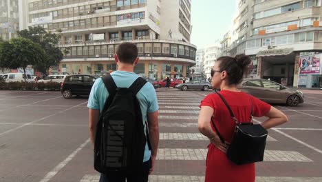 Couple-travelers-waiting-at-the-crossing-to-cross-the-streets-of-Casablanca