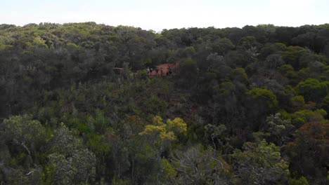 Aerial-rising-drone-shot-flying-away-from-people,-surrounded-by-forest-and-australian-nature,-on-a-warm-and-sunny-evening,-in-Cape-York,-Queensland,-Australia