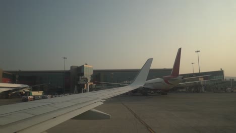 Window-View-Of-An-Airplane's-Wing-On-The-Runway-Of-Chhatrapati-Shivaji-Maharaj-International-Airport-In-Mumbai,-India---trucking-shot