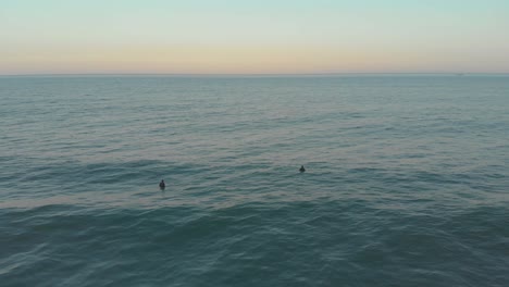 Surfers-learning-to-balance-on-the-mild-ocean-waters-of-beach-Santinho-at-evening-golden-hour