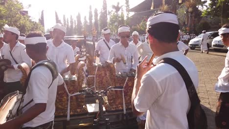 Músicos-Tocan-Gamelan-Baleganjur-En-La-Ceremonia-Del-Templo-Al-Aire-Libre-En-Bali-Indonesia-Durante-El-Amanecer,-Gongs-De-Percusión-Metálicos-Dorados,-Samuan-Tiga
