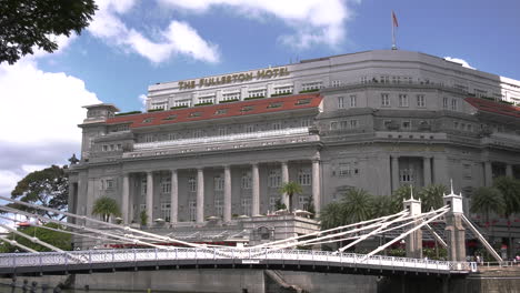 A-time-lapse-footage-of-the-iconic-The-Fullerton-Hotel-in-Singapore-on-a-sunny-afternoon-with-clear-blue-sky,-and-Cavenagh-bridge