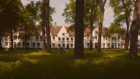 People-walks-in-front-of-Historic-landmark-of-Beguinage-convent-in-Bruges,-Belgium