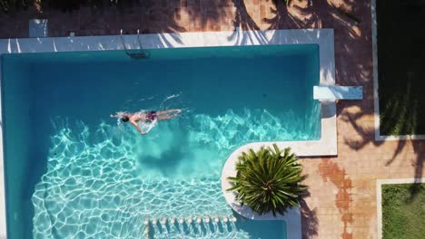 Man-Swimming-in-Luxury-Swimming-Pool:-Ascending-Aerial-Birds-eye-View