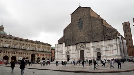 Blick-Auf-Die-Basilika-San-Petronio-Mit-Touristen,-Die-über-Die-Piazza-Maggiore-Laufen