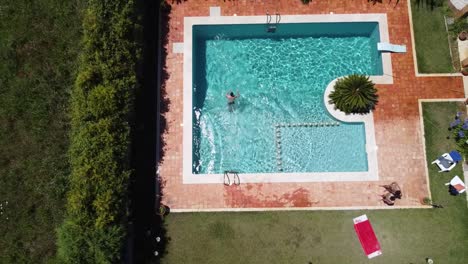 Luftaufnahme-Eines-Mannes,-Der-Im-Sommer-In-Ein-Luxuriöses-Schwimmbad-Springt