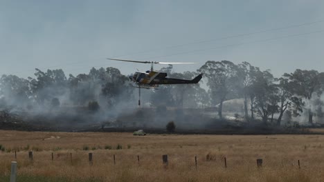 Helicopter-approaching-dam-with-other-fire-crew-in-background-near-grass-fire