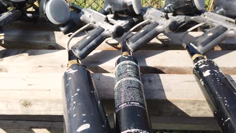 Black-paintball-weapons-arranged-on-a-wooden-bench-in-nature