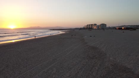 Luftaufnahme-Von-Menschen,-Die-Den-Sonnenuntergang-Am-Strand-In-Costa-Da-Caparica,-Portugal,-Genießen