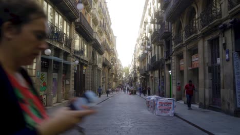 Forward-shot-through-long-central-street-in-Barri-Gothic-quarter-of-Barcelona-with-people-starting-their-day-in-the-morning-and-walking-over-pavement