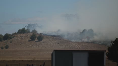 Grass-fire-burning-on-farmland-behind-shed