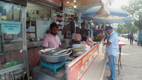 Kunde-Steht-Und-Kauft-Traditionelles-Indisches-Essen-An-Einem-Stand-In-Gurugram,-Indien