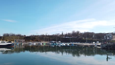 Der-Neu-Erbaute-Hafen-In-Kraimorie---Festgemachte-Boote,-Menschen-Für-Einen-Spaziergang,-Ruhige-See-An-Einem-Sonnigen-Wintertag