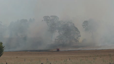 Lone-fire-engine-truck-spraying-water-on-edge-of-a-huge-grass-fire-to-help-control-the-spread-on-warm-windy-day