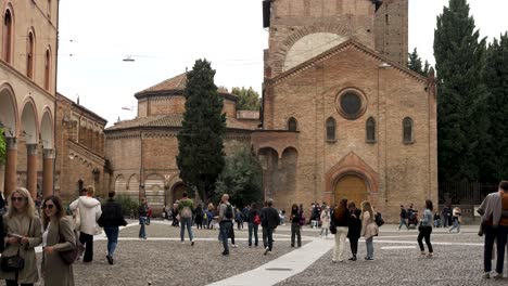 Touristen-Gehen-über-Die-Piazza-Santo-Stefano-Mit-Der-Basilika-Von-Santo-Stefano-Im-Hintergrund-In-Bologna