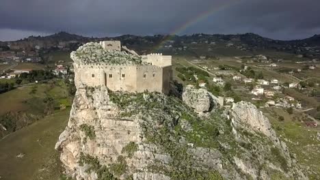 drone-shot-moving-backwards-from-Mussomeli-Castle-with-a-stunning-rainbow-raising-from-the-castle-while-the-drone-is-flying-away