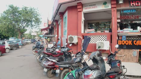 Urban-City-Street-Parked-Motorbikes-Outside-Bookstore,-India