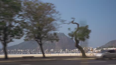 POV-Aufnahme-Aus-Dem-Auto,-Die-Einen-Wunderschönen-Sandstrand-Und-Den-Zuckerhut-Im-Hintergrund-Zeigt-–-Rio-De-Janeiro,-Brasilien