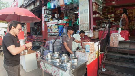 Touristen-Kaufen-Und-Probieren-Indische-Köstlichkeiten-Bei-Einem-Straßenverkäufer-In-Indien