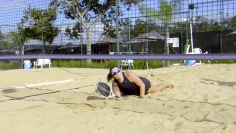 Beach-Tennisspieler-Macht-Einen-Sprung-In-Den-Sand,-Um-Den-Ball-Zu-Schlagen,-Epische-Parade,-Fangen,-Fallen,-Starke-Mentalität-Im-Wettbewerb,-Augen-Auf-Den-Preis-Gerichtet,-Gewinnen,-Weibliches-Teamplay,-Sonniges-Freizeitturnier