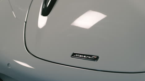 McLaren-logo-on-white-super-car-in-studio,-light-reflecting,-close-up