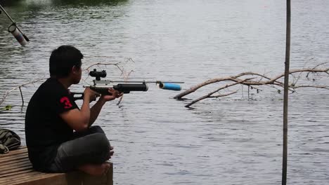 A-man-hunts-for-fish-on-the-edge-of-an-artificial-lake-in-Depok,-Indonesia